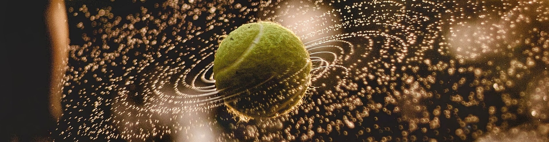 Drehender nasser Tennisball in der Luft - Tennisreise mit Maxiflug